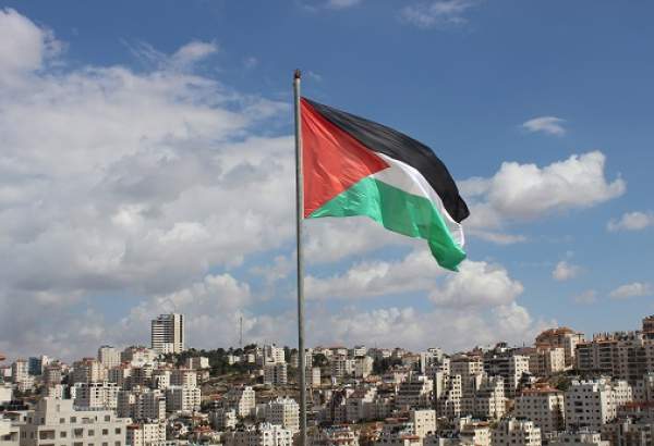 Palestinian youths hoist Palestinian flags in al-Quds