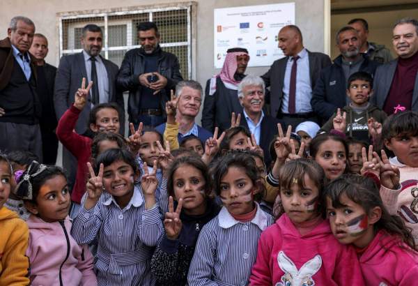 Children gesture as they pose for a photo with members of a European Union delegation and the Palestinian Education Minister Marwan Awartani at a school facing demolition by Israel in Khashm el-Karm, south of the village of Yatta in the occupied West Bank on January 25, 2023 [HAZEM BADER/AFP via Getty Images]